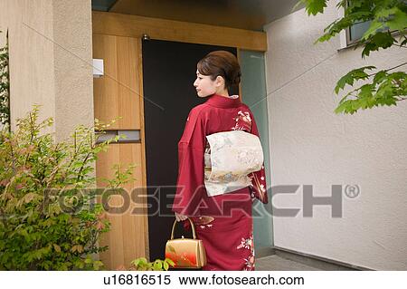 A young woman wearing kimono standing in front of door View Large Photo Image Stock Photography - A young woman wearing kimono standing in front of door. Fotosearch
