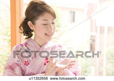Stock Photograph - A young woman wearing yukata holding glass bowl. Fotosearch