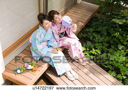 Stock Photo - Two young women wearing yukata sitting on porch. Fotosearch