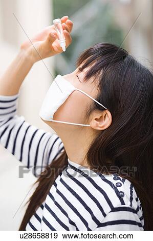 Stock Photo - A woman applying eye drop. Fotosearch