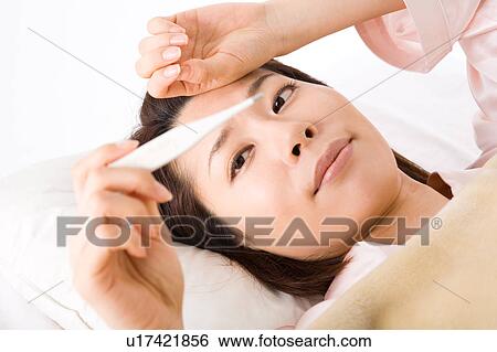 A woman looking at thermometer View Large Photo Image Stock Photograph - A woman looking at thermometer. Fotosearch
