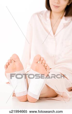 A woman putting detox pads on her feet View Large Photo Image Stock Photography - A woman putting detox pads on her feet. Fotosearch