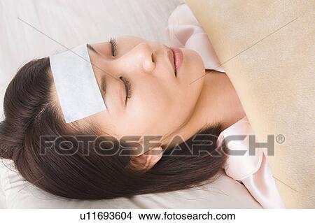 A woman sleeping with cooling sheet on her forehead View Large Photo Image Picture - A woman sleeping with cooling sheet on her forehead. Fotosearch
