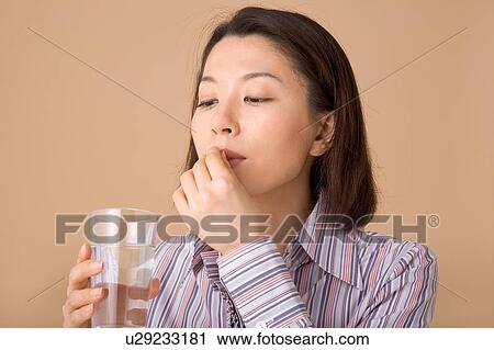 Stock Image - A woman taking pills. Fotosearch