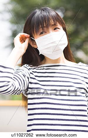 Stock Image - A woman wearing mask. Fotosearch