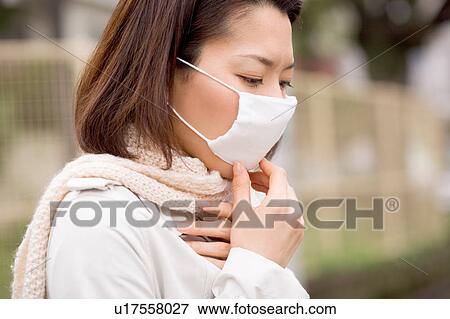 Stock Photo - A woman wearing mask. Fotosearch