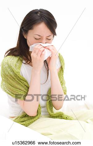 A young woman blowing nose on tissue View Large Photo Image Stock Photograph - A young woman blowing nose on tissue. Fotosearch