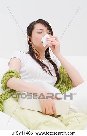 A young woman blowing nose on tissue View Large Photo Image Stock Photography - A young woman blowing nose on tissue. Fotosearch