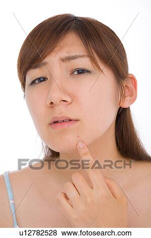 A young woman looking at pimple on her face View Large Photo Image Stock Photo - A young woman looking at pimple on her face. Fotosearch