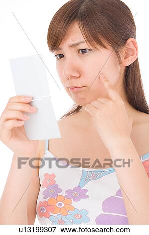 A young woman looking at pimple on her face View Large Photo Image Stock Photo - A young woman looking at pimple on her face. Fotosearch