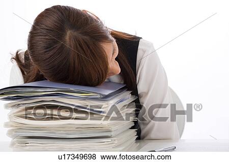 Stock Photo - A young woman sleeping at her desk. Fotosearch