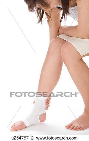 A young woman touching her ankle View Large Photo Image Stock Image - A young woman touching her ankle. Fotosearch