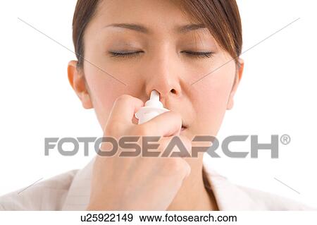 Stock Photo - A young woman using nasal spray. Fotosearch