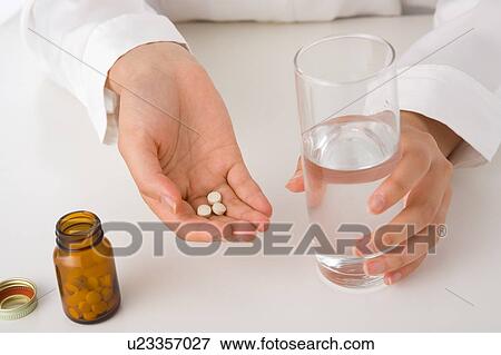 A young woman's hand holding a glass of water and pills View Large Photo Image Stock Photo - A young woman's hand holding a glass of water and pills. Fotosearch