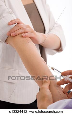 Stock Image - Doctor injecting arm of a woman. Fotosearch