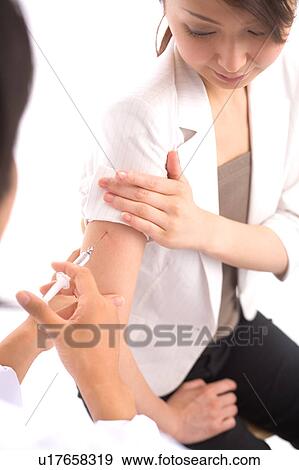Stock Photo - Doctor injecting arm of a woman. Fotosearch