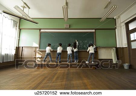 Stock Image - Children writing on blackboard. Fotosearch