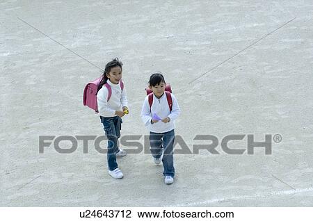 Stock Image - Girls standing in schoolyard. Fotosearch
