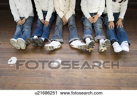 Stock Image - Legs of children sitting in corridor. Fotosearch