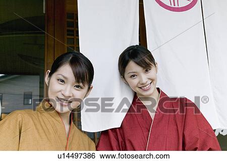 Stock Photograph - Two young women standing in front of restaurant. Fotosearch