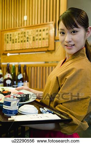 Stock Photograph - Waitress carrying a tray of sushi. Fotosearch