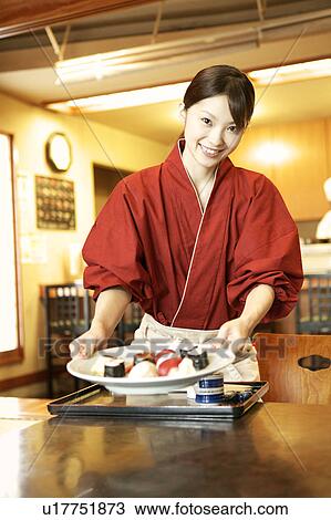 Stock Image - Waitress serving sushi. Fotosearch