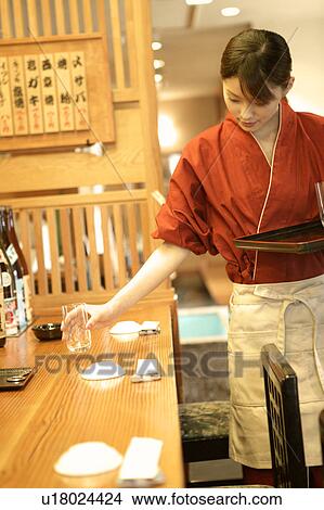 Picture - Waitress setting table at Japanese restaurant. Fotosearch