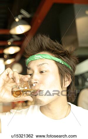 Stock Image - Young man drinking a glass of beer. Fotosearch
