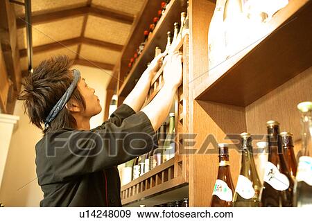 Young man looking at bottle shelf View Large Photo Image Stock Photo - Young man looking at bottle shelf. Fotosearch