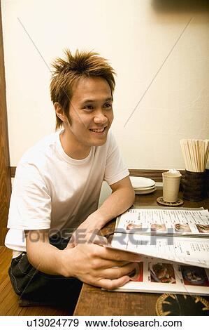Stock Photo - Young man looking at menu. Fotosearch