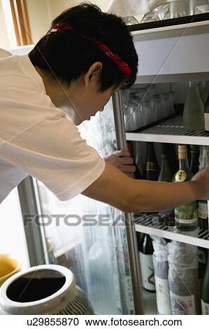 Stock Image - Young man looking into refrigerator. Fotosearch