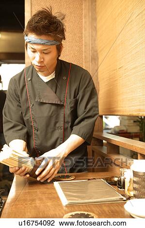 Stock Image - Young man setting chopsticks. Fotosearch