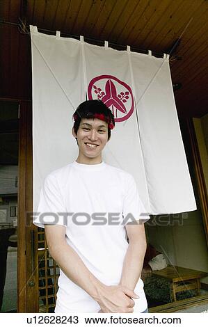 Stock Image - Young man standing in front of restaurant. Fotosearch