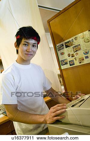 Young man working on cash register View Large Photo Image Stock Image - Young man working on cash register. Fotosearch