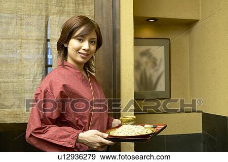 Young woman carrying a tray of noodles View Large Photo Image Stock Photo - Young woman carrying a tray of noodles. Fotosearch