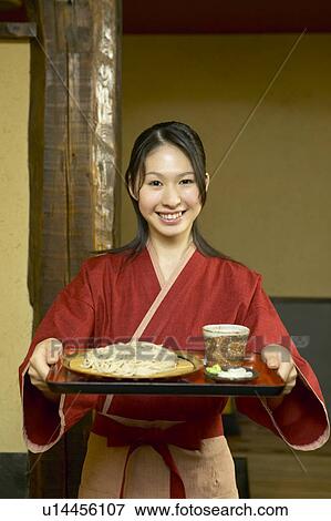Young woman carrying a tray of noodles View Large Photo Image Stock Photo - Young woman carrying a tray of noodles. Fotosearch