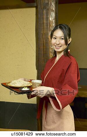 Young woman carrying a tray of noodles View Large Photo Image Stock Photo - Young woman carrying a tray of noodles. Fotosearch