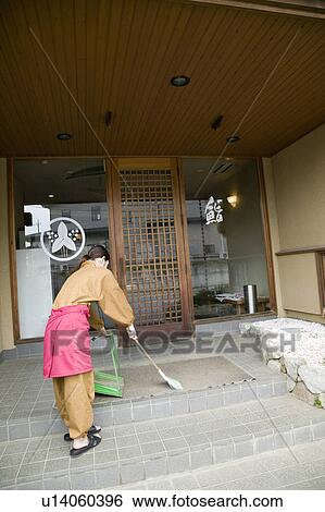 Stock Photograph - Young woman cleaning in front of restaurant. Fotosearch