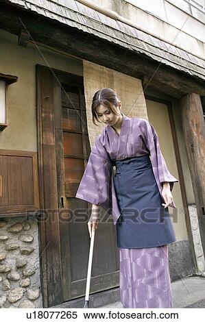 Stock Photography - Young woman cleaning with broom. Fotosearch