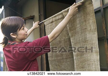 Young woman hanging store curtain View Large Photo Image Stock Image - Young woman hanging store curtain. Fotosearch