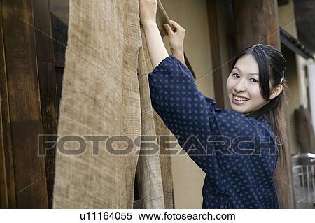 Stock Photography - Young woman hanging store curtain. Fotosearch