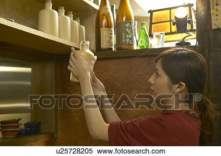Young woman holding a bottle of alcohol View Large Photo Image Stock Photography - Young woman holding a bottle of alcohol. Fotosearch