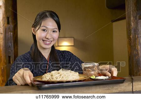 Stock Photo - Young woman holding a tray of noodles. Fotosearch
