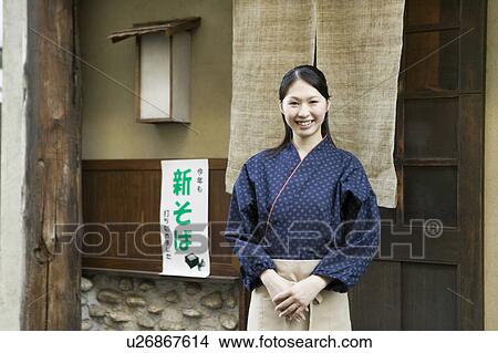 Picture - Young woman standing in front of restaurant. Fotosearch