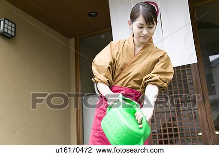 Young woman watering in front of restaurant View Large Photo Image Stock Image - Young woman watering in front of restaurant. Fotosearch