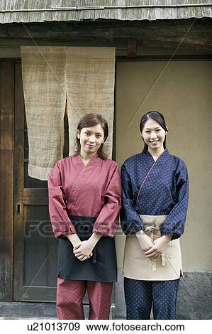 Stock Photo - Young women standing in front of restaurant. Fotosearch