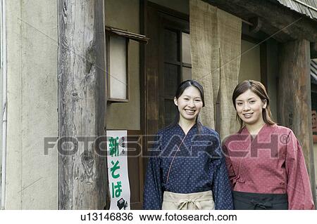 Stock Photograph - Young women standing in front of restaurant. Fotosearch