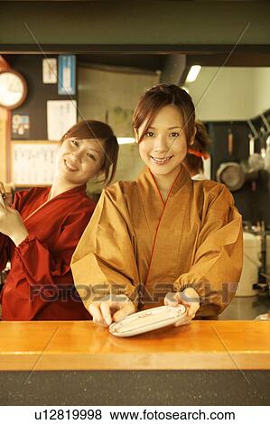 Stock Photo - Young women working in restaurant kitchen. Fotosearch