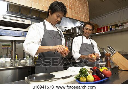 Stock Image - Two chefs peeling onion. Fotosearch