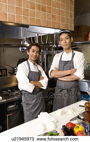 Two chefs standing in restaurant kitchen View Large Photo Image Stock Image - Two chefs standing in restaurant kitchen. Fotosearch